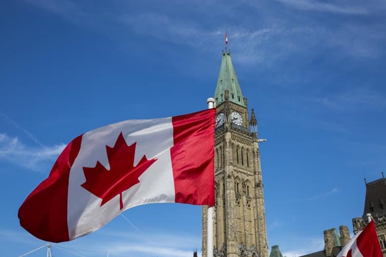 Un drapeau canadien flottant devant la tour de la Paix, à Ottawa.