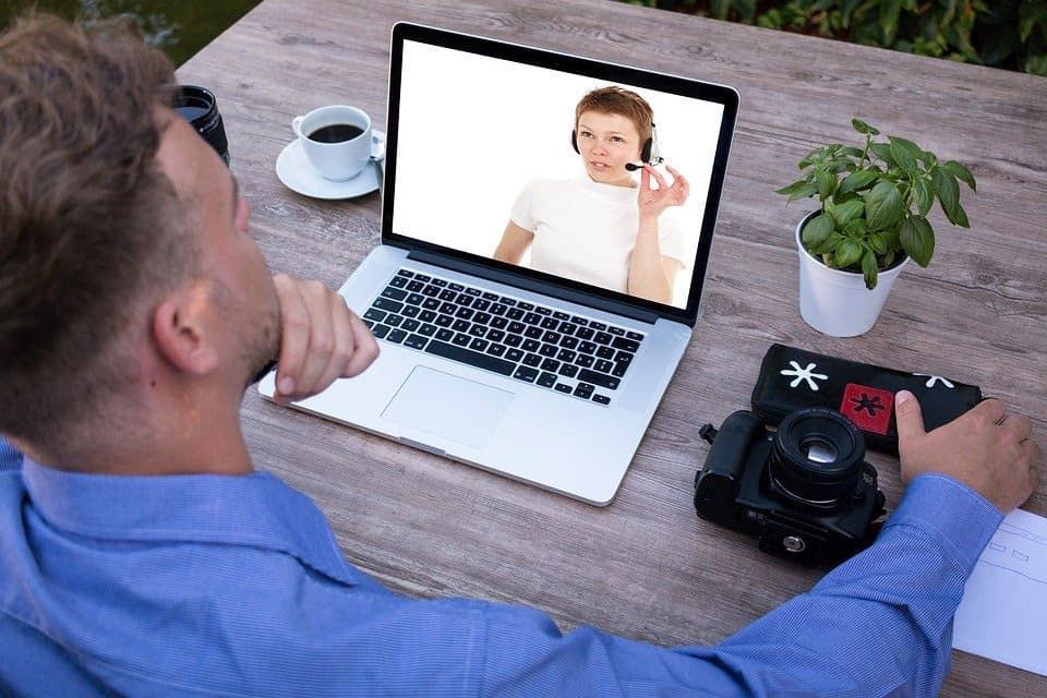 Une personne apprenante devant un ordinateur portable, son enseignante visible à l'écran pendant une séance en direct.